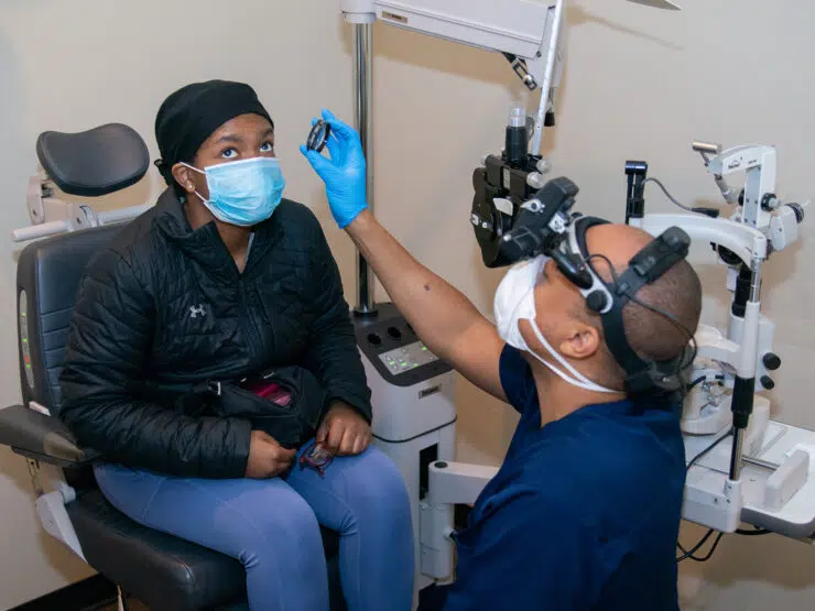 A doctor uses a small tool to examine a patient's eyes.