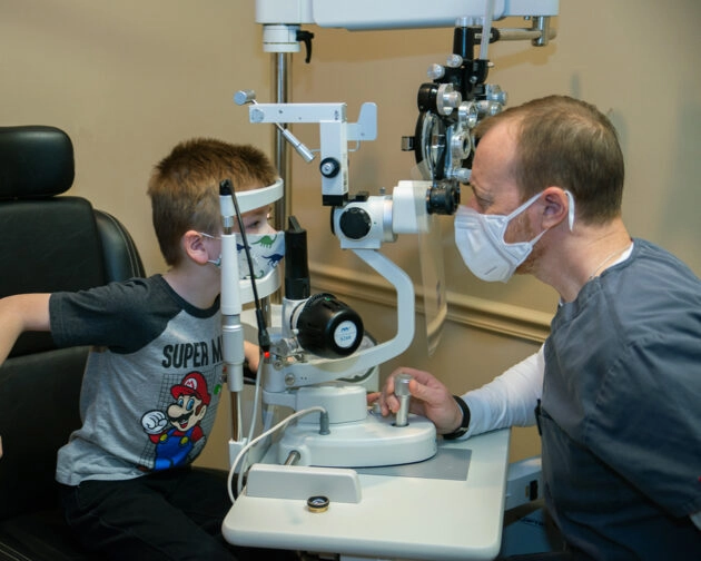 A young boy getting his eyes examined by a doctor.