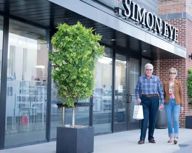An older couple walks holding hands outside a Simon Eye office.