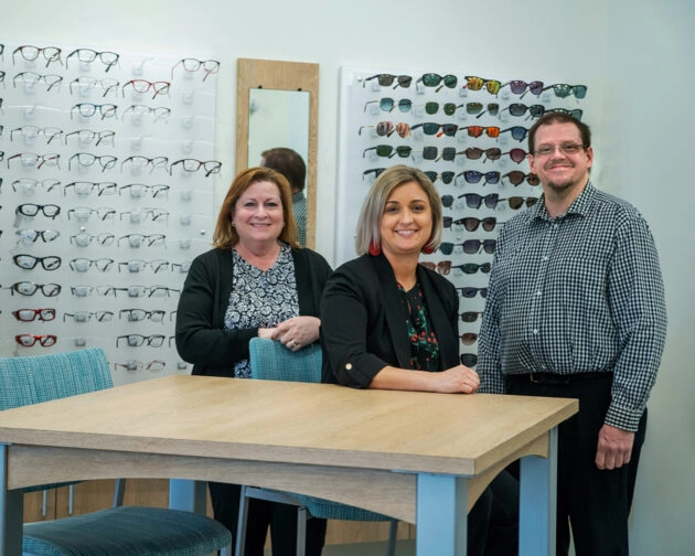 Three people in front of displays of glasses at Simon Eye Rehoboth.