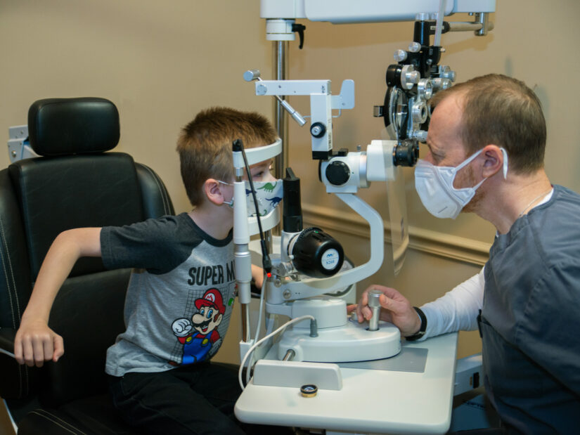 A young boy getting his eyes examined by a doctor.