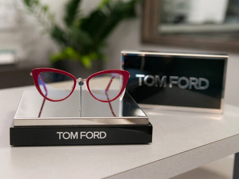A pair of red glasses on display next to a display of the Tom Ford logo.