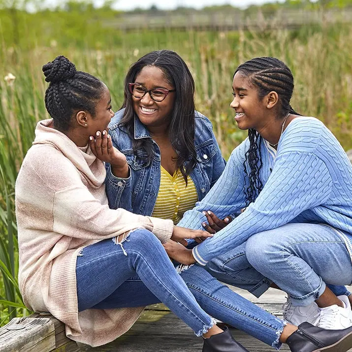 A group of children huddle together in grass.