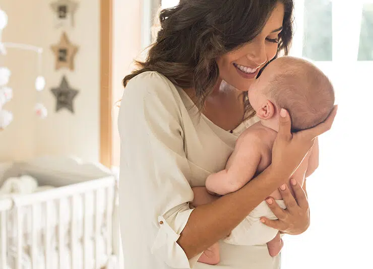 Young mother holding her baby in the nursery