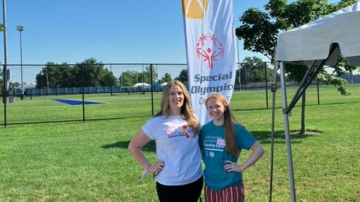 Two women standing near a Special Olympics banner.