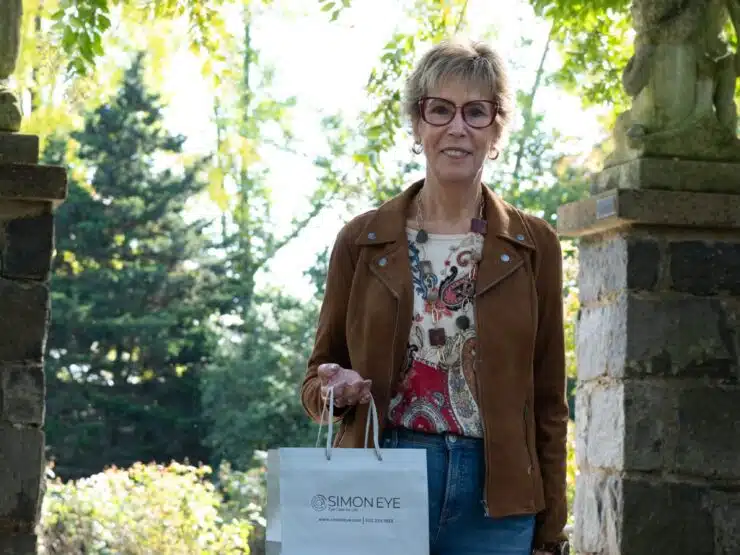 woman with glasses holding simon eye bag outside