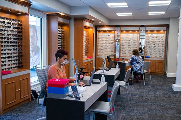 Staff member working on laptop in front of glasses display case