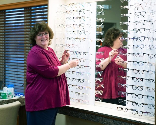 A person standing in front of a display of glasses.