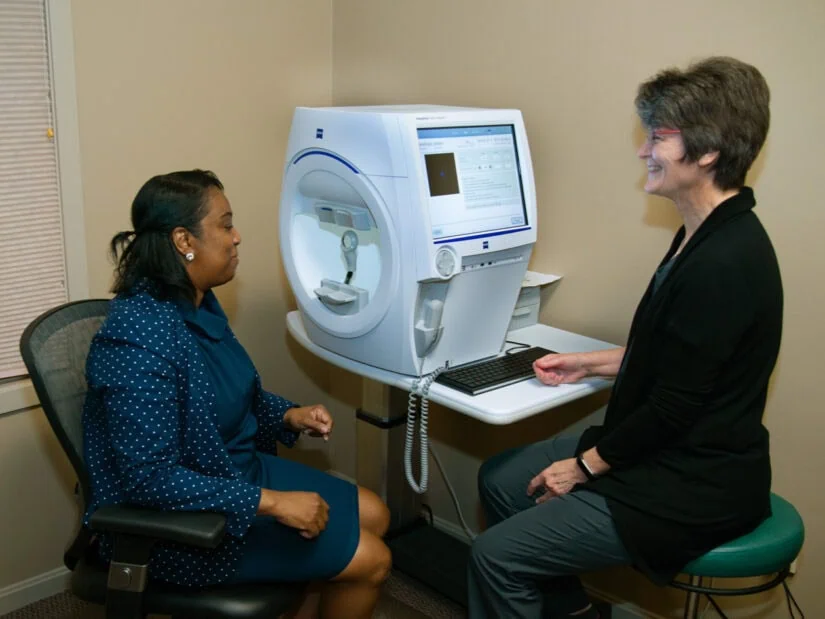 A patient and a doctor in front of eye exam equipment.