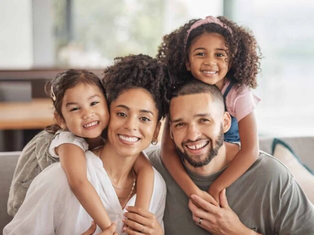 A man and woman with two children sitting on a couch.