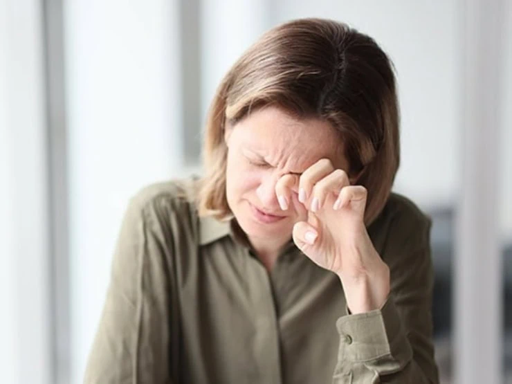 Exhausted, tired female manager sitting with her eyes closed at her desk in office.